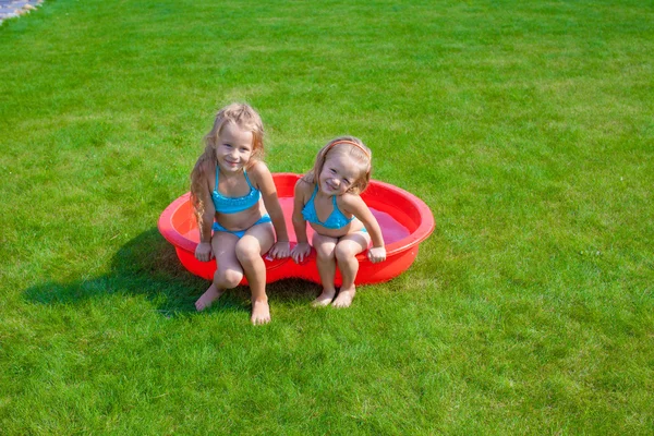 两个小姐妹 frolicing 和溅在自己院子里小小的池子 — 图库照片