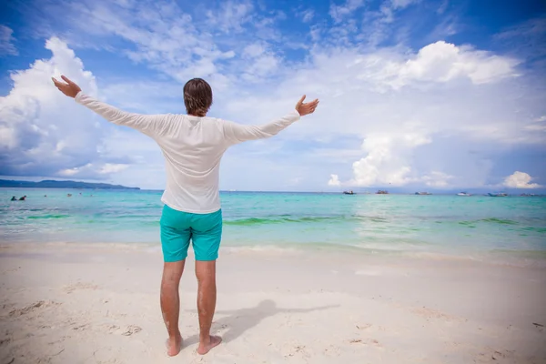 回来查看的年轻男子传播他的手臂站在白色的沙滩上 — 图库照片