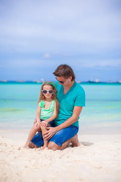 年轻的父亲和他的小女儿坐在热带的白色沙滩上 — 图库照片