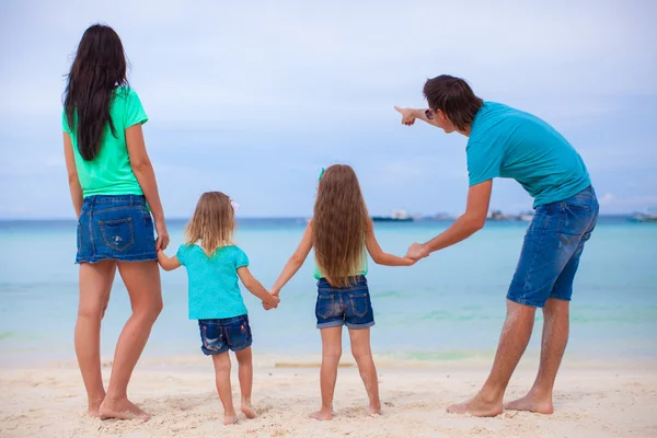 Pohled zezadu na mladé rodiny s dvěma dcerami na exotické pláži slunečného dne — Stock fotografie