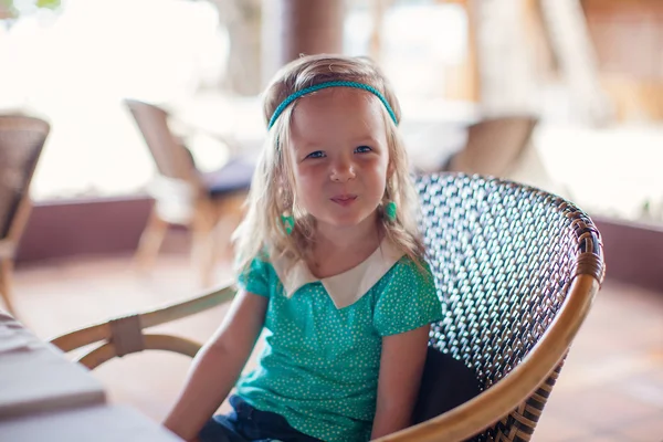 Kleines Mädchen sitzt im Stuhl im Restaurant und wartet auf ihr Essen — Stockfoto