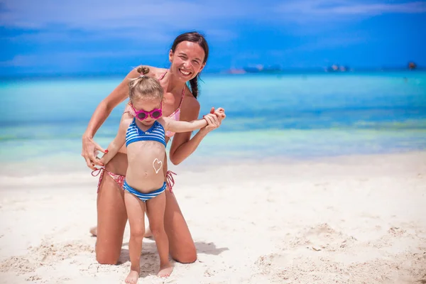 Young beautiful mother and her adorable little daughter have fun at tropical beach — Stock Photo, Image