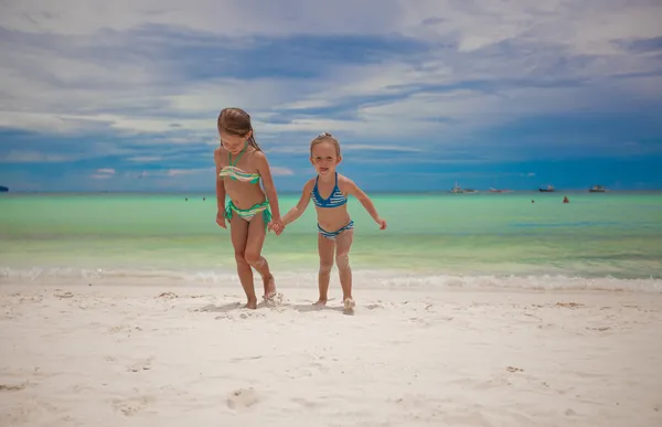 Dos hermanas pequeñas en bonitos trajes de baño fuera del mar en la playa tropical exótica — Foto de Stock