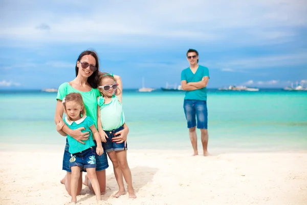 Mamá con sus hijas lindas en primer plano y papá en el fondo en la playa — Foto de Stock