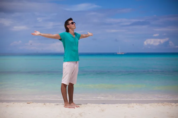 Young man spread his arms standing on white sandy beach — Stock Photo, Image