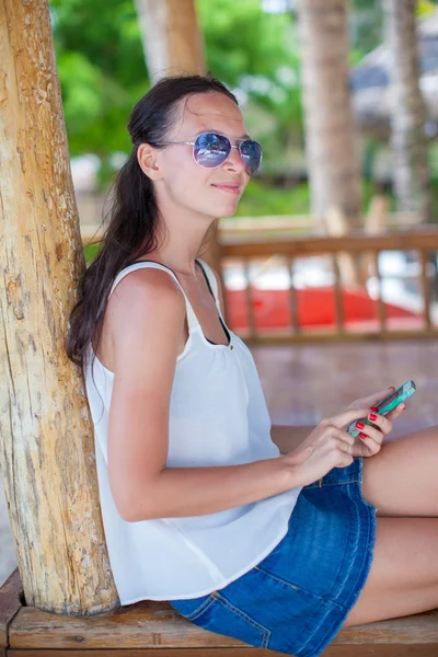 Mujer joven sentada en el puente y mirando a su teléfono — Stockfoto