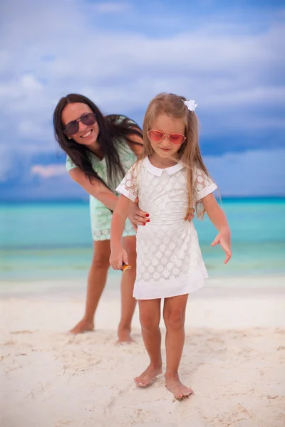 Närbild lilla flicka håller unga mamman på stranden — Stockfoto