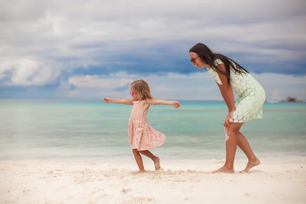 Niña con su madre bailando en la playa de arena blanca en un día soleado — Foto de Stock