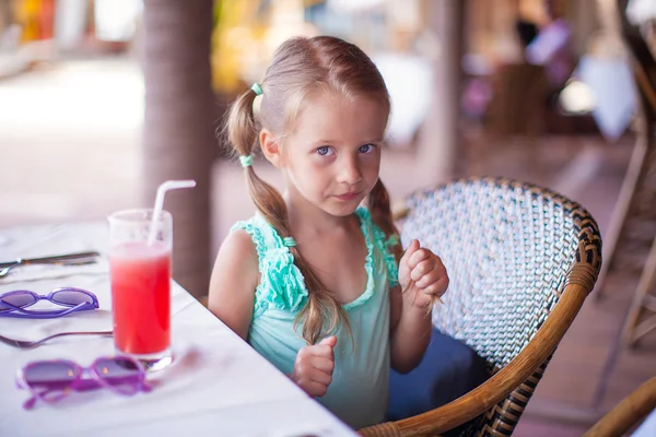 Little girl sitting in chair at restaurant waiting for her food Royalty Free Stock Images