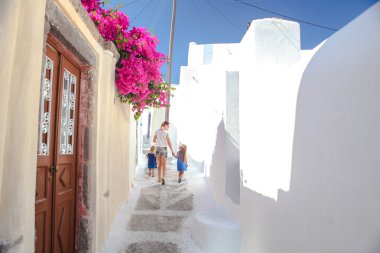 Beautiful cobbled streets with walking family on the old traditional White House in Emporio Santorini, Greece clipart