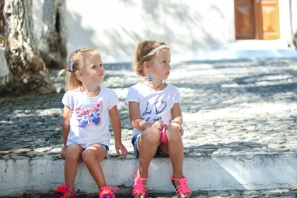 Молодые очаровательные девушки, сидящие на улице в старой греческой деревне Эмморио, Санторини — стоковое фото
