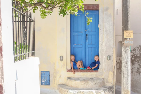 Two little adorable girls sitting on doorstep of old house in Emporio village, Santorini, Greece — Stock Photo, Image