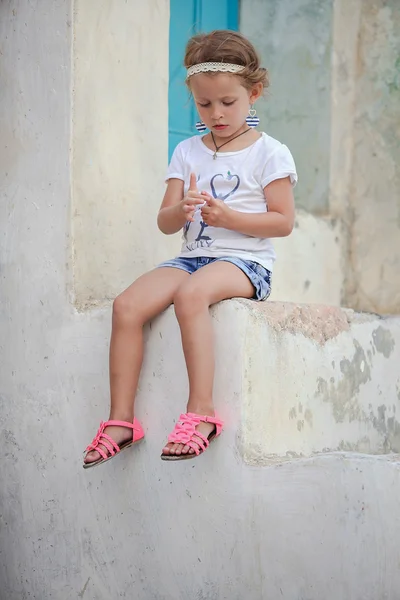 Adorable petite fille assise sur les marches de la vieille maison dans le village d'Emporio, Santorin, Grèce — Photo