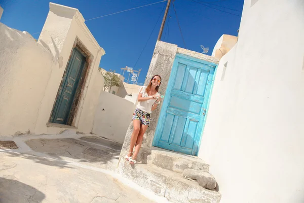 Happy young woman talking on phone and walking through the narrow old streets in Greek village of Emporio — Stock Photo, Image