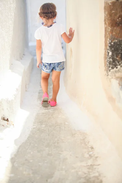 Adorable chica caminando sola en las calles estrechas del pueblo de Emporio en la isla Santorini, Grecia —  Fotos de Stock