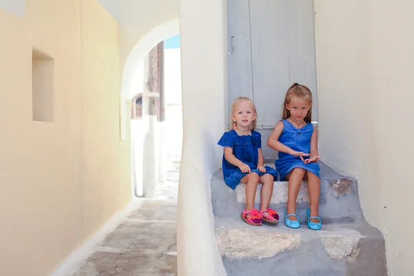 Two little adorable girls sitting on doorstep of old house in Emporio village, Santorini, Greece — Stock Photo, Image