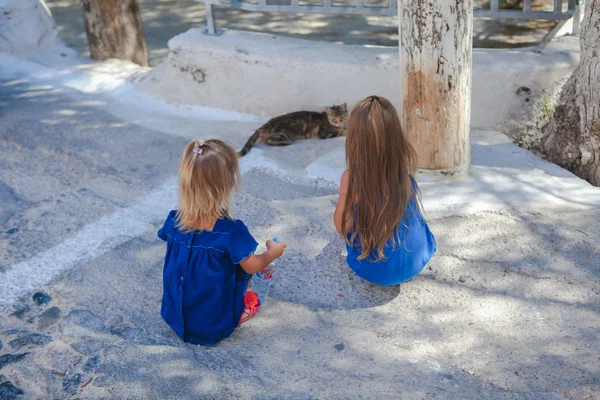 Little girls play with a cat on the streets of Emporio, Santorini, Greece — Stock Photo, Image