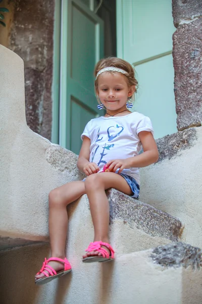 Adorable niña sentada en los escalones de la vieja casa en Emporio village, Santorini, Grecia —  Fotos de Stock