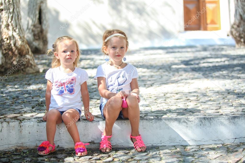 Young charming girls sitting at street in old Greek village of Emporio, Santorini