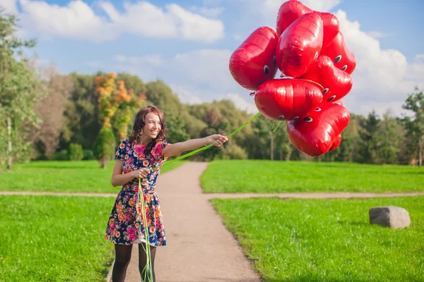 Giovane donna attraente felice in bel vestito divertirsi con palloncini rossi fuori — Foto Stock