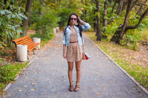 Fashion young beautiful girl walks in the park on a sunny autumn day — Stock Photo, Image