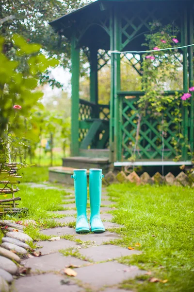 Bright fashionable rubber boots in the garden background of wooden pergolas — Stock Photo, Image