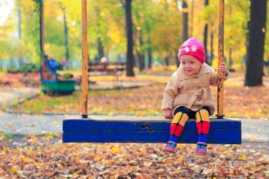 küçük güzel bir kız bir salıncak sonbahar Park eğlenmek