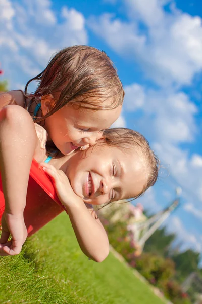 Dos encantadoras hermanitas felices divirtiéndose en una pequeña piscina en el patio al aire libre — Foto de Stock