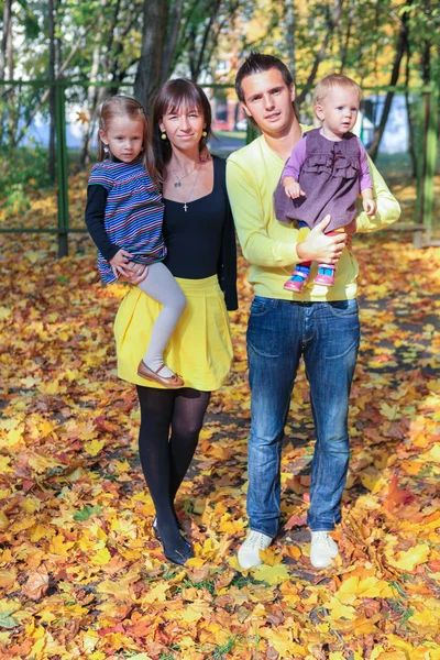 Jeune charmante famille de quatre personnes marchant dans un parc d'automne jaune — Photo