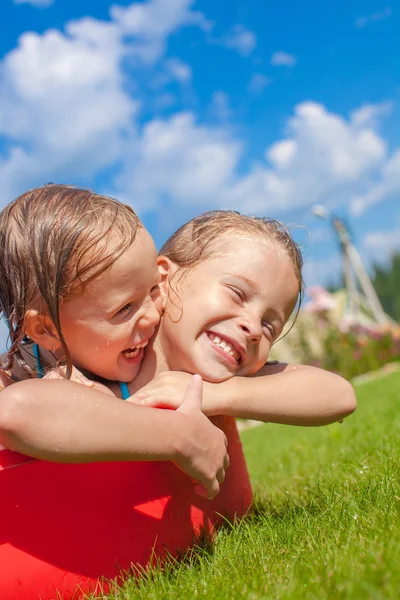 Two charming little happy sisters having fun in small pool on the courtyard outdoor — Stock Photo, Image