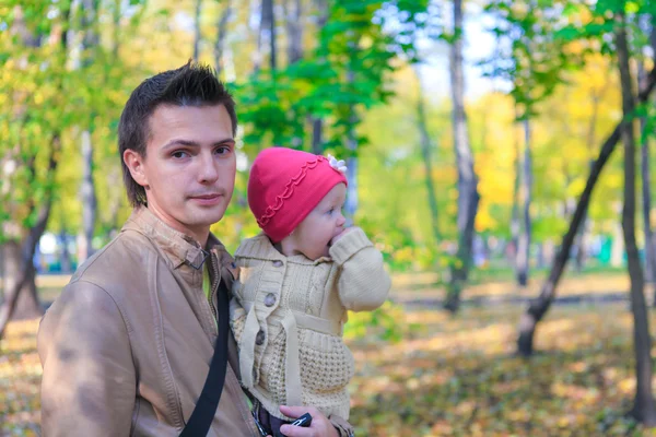 Jovem pai andando com sua filhinha fofa no parque de outono ao ar livre — Fotografia de Stock