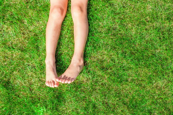 Primo piano di due gambe di una giovane ragazza sull'erba sul prato — Foto Stock