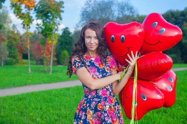 Nahaufnahme einer jungen attraktiven Frau in schönem Kleid mit roten Luftballons — Stockfoto