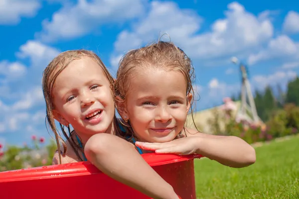 Two cute little happy girls having fun in small pool on the courtyard outdoor and enjoy their vacation Stock Photo