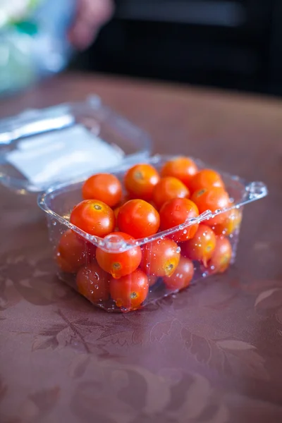 Close-up box with a red cherry tomatoes on kitchen table — Stock Photo, Image