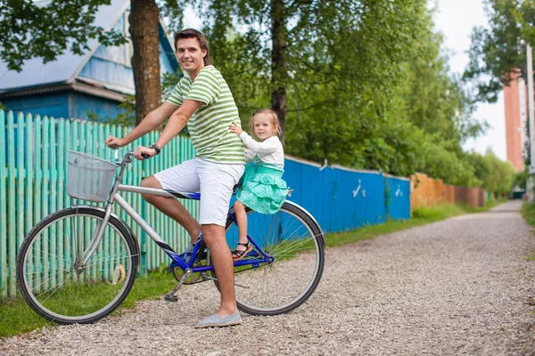 Ung pappa rullar sin söta charmiga dotter på en cykel på landsbygden — Stockfoto