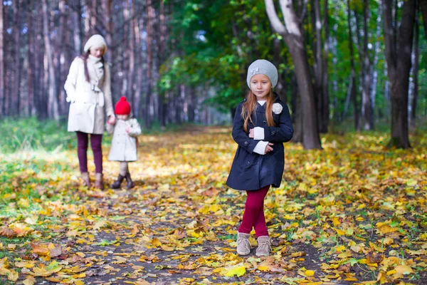 Giovane madre e la sua adorabile figlia a piedi in giallo foresta autunnale in una calda giornata di sole — Foto Stock