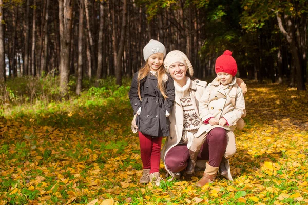 Giovane madre con la sua meravigliosa bella figlia passeggiata nel parco autunnale in una giornata di sole caldo — Foto Stock