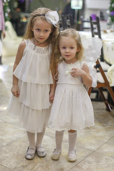 दो सुंदर लड़कियों ने सुंदर पोशाक पहने हुए अपने क्रिसमस उपहारों की प्रतीक्षा करते हुए हिमस्खलन — स्टॉक फ़ोटो, इमेज