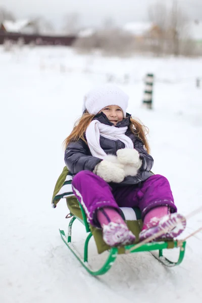 Adorable little girl on a sled at winter sunny day — Stock Photo, Image