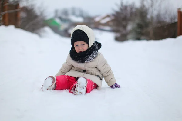 Little sad girl sitting on the snow at winter sunny day — Stock Photo, Image