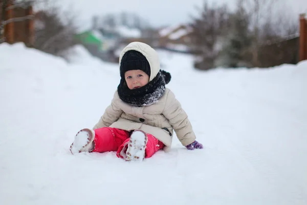 Liten, trist jente som sitter i snøen om vinteren, solskinnsdag – stockfoto