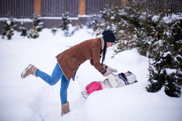 Happy young mother with her little cute daughter having fun in the backyard on a winter day — Stock Photo, Image