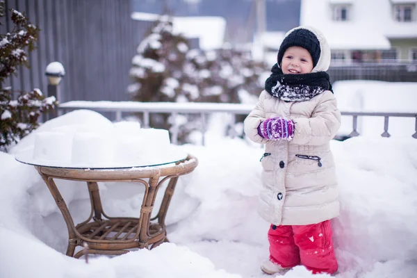 Klein grappig en vrolijk meisje plezier in de tuin op zonnige winterdag — Stockfoto