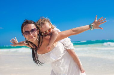 genç güzel anne ve sevimli küçük kız beyaz plaj üzerinde kuş gibi kollarını açtı