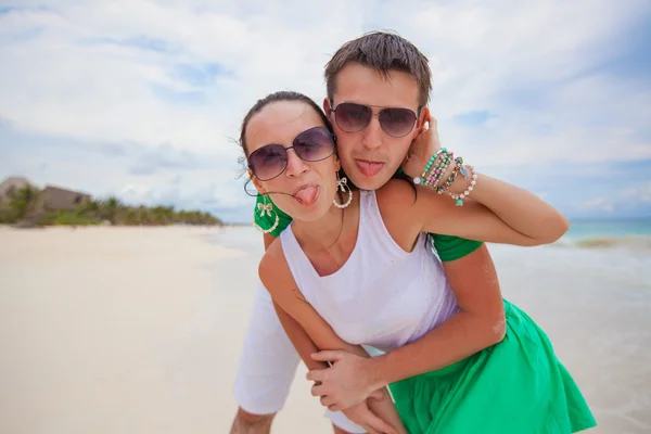 Joven hermosa y feliz pareja mostrando la lengua en la cámara en una playa blanca — Foto de Stock