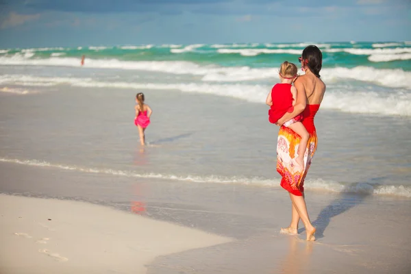 Mother with two adorable daughters walking at exotic beach on sunny day — Stock Photo, Image