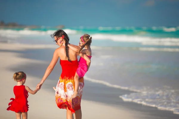 Mother and two adorable daughters walking at exotic beach on sunny day — Stock Photo, Image