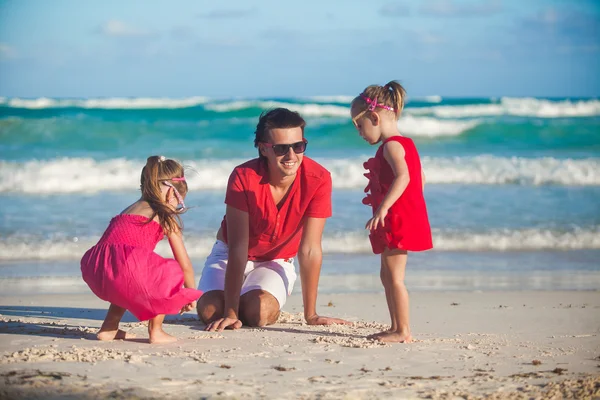 Unga far och hans bedårande lilla döttrar spelar på stranden — Stockfoto