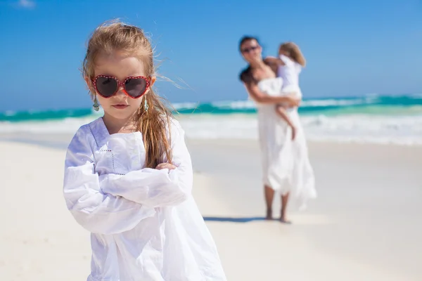 Portrait of cute girl and her mother with little sister in the background at tropical beach — Stock Photo, Image